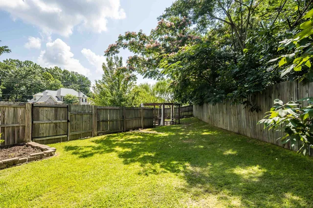 a view of a backyard with a tree and wooden fence