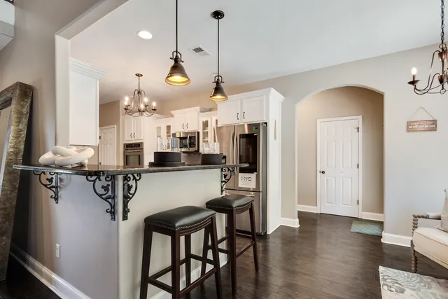 a kitchen with a refrigerator a sink dishwasher a stove and a dining table with wooden floor