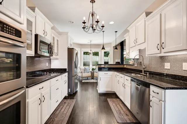 a kitchen with granite countertop a stove top oven a sink a counter space and cabinets