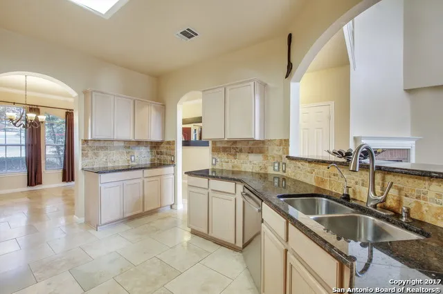 a kitchen with granite countertop a sink and white cabinets