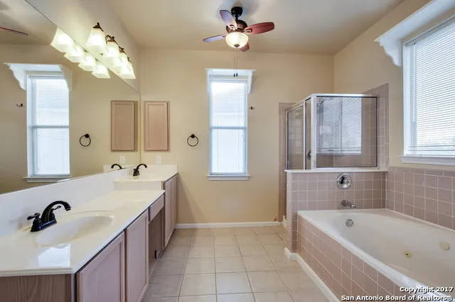 a bathroom with a tub a sink double vanity and a mirror
