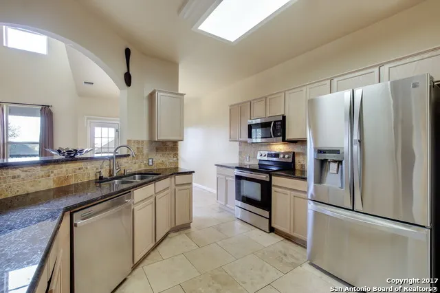 a kitchen with stainless steel appliances granite countertop a refrigerator sink and stove