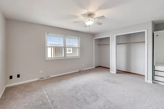 a view of an empty room with chandelier fan and windows