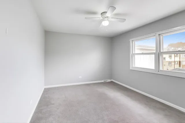 an empty room with windows and ceiling fan