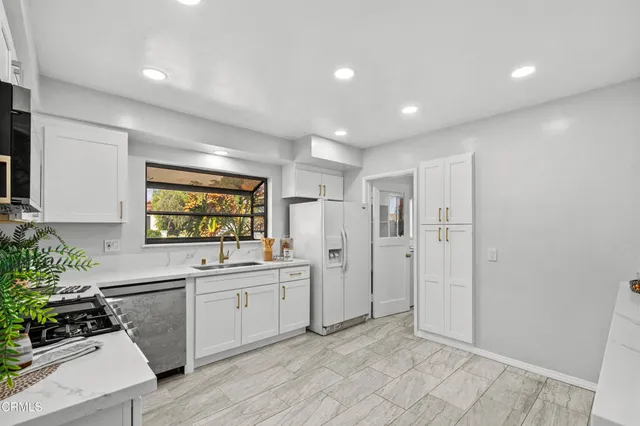 a kitchen with white cabinets and sink