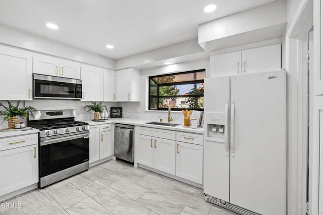 a kitchen with white cabinets stainless steel appliances and a sink