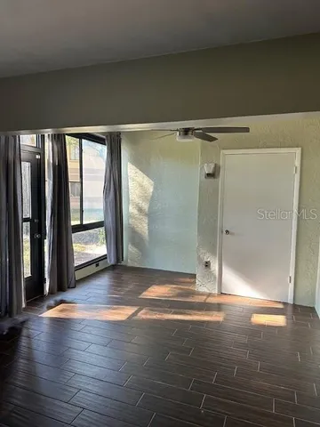 a view of an empty room with wooden floor and a window