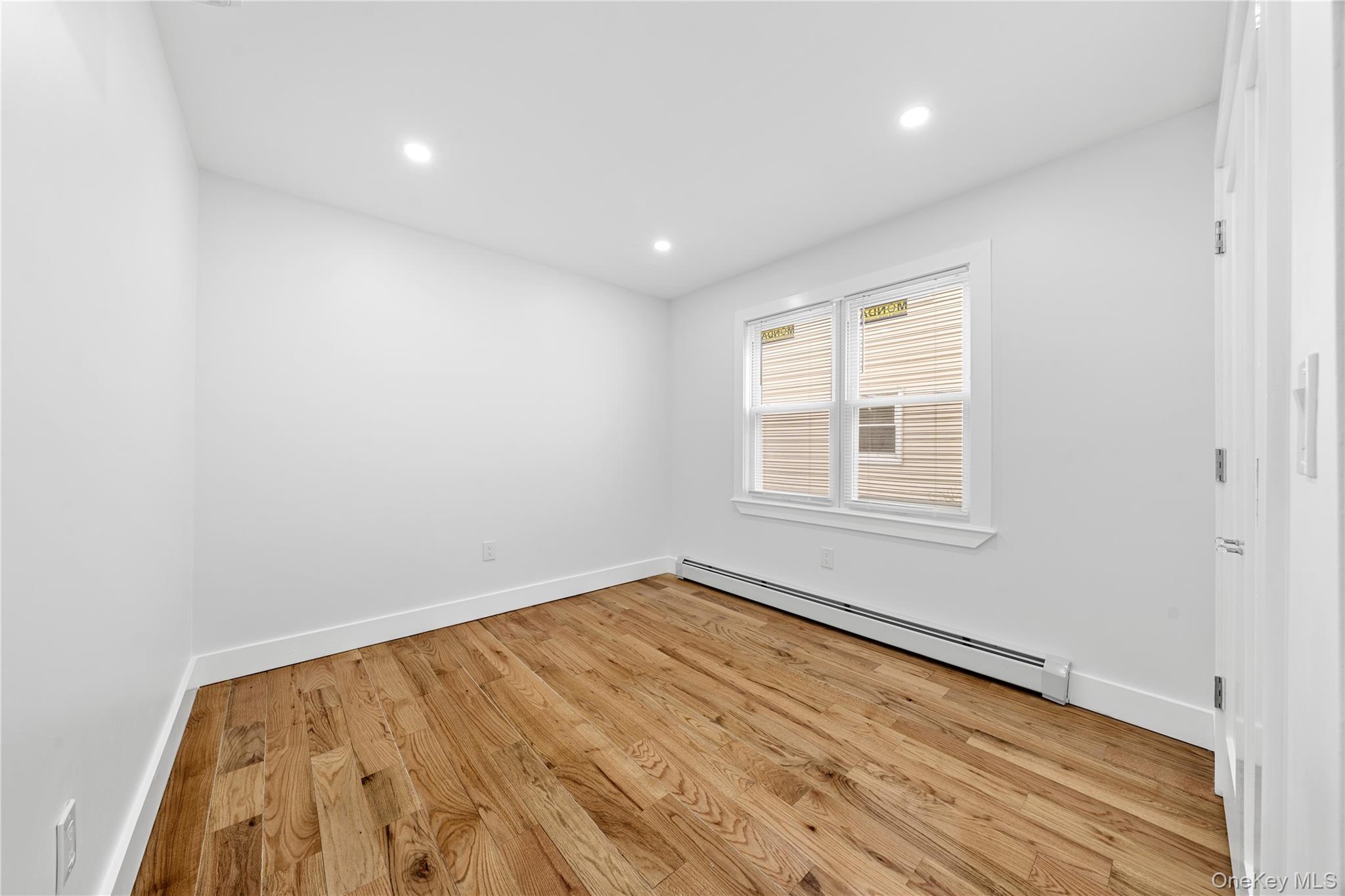 245-33 147th Road, Unit 1 Queens, NY 11422 - Photo 11 of 15 an empty room with wooden floor and windows
