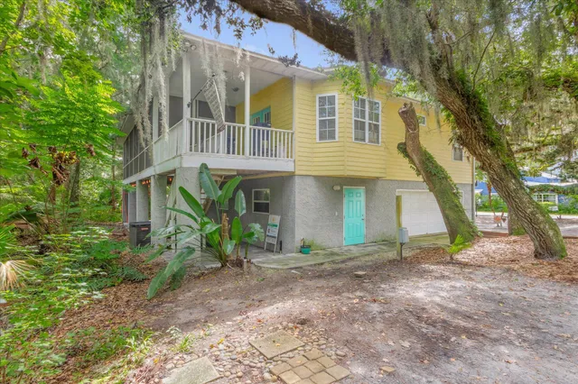 a view of a white house with large windows and a tree