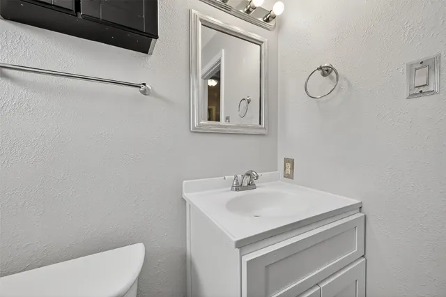 a bathroom with a toilet sink vanity and mirror