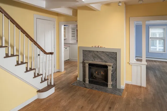 a view of a livingroom with wooden floor and a fireplace