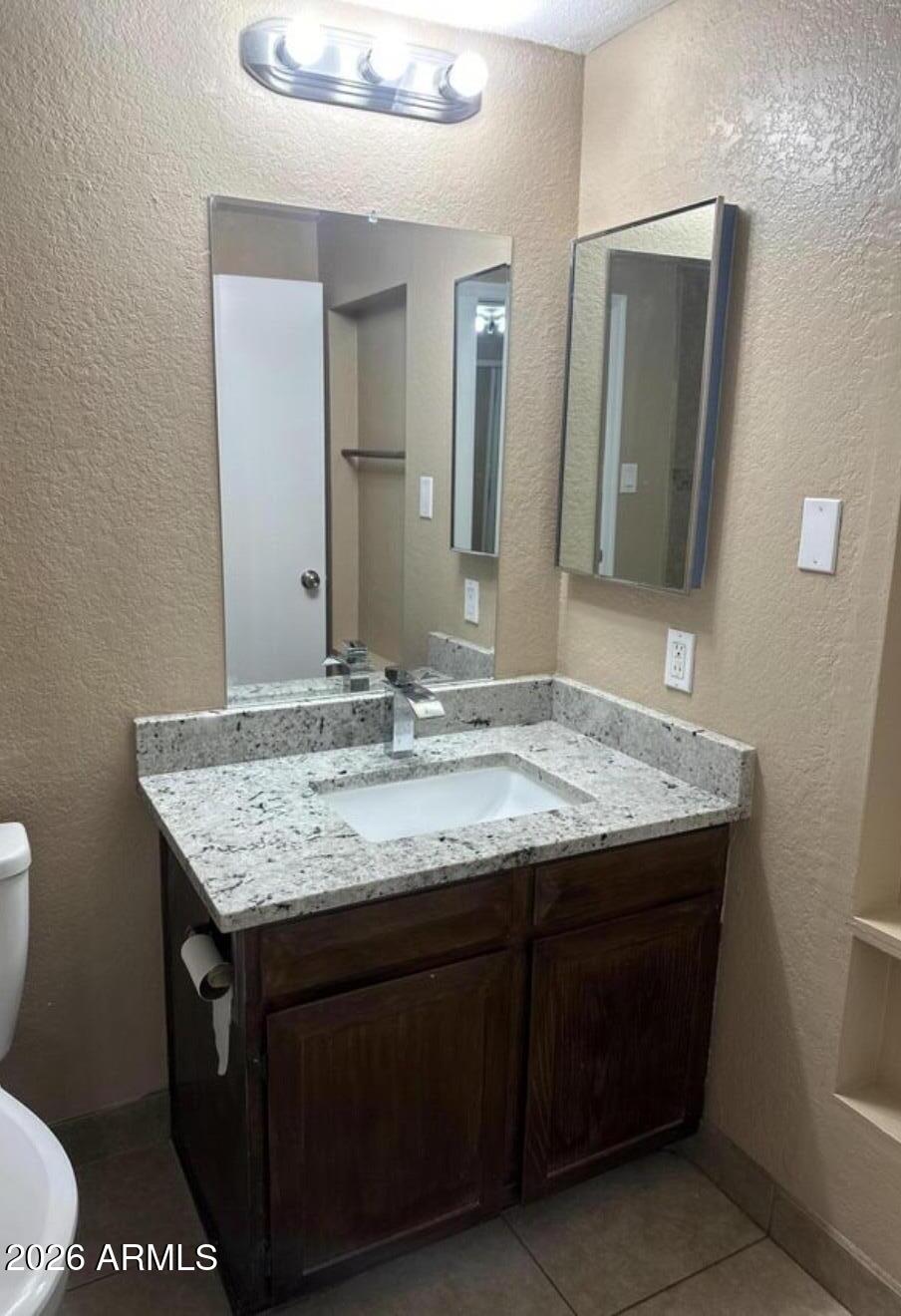 2916 North 87th Lane Phoenix, AZ 85037 - Photo 16 of 16 a bathroom with a granite countertop sink a toilet and mirror