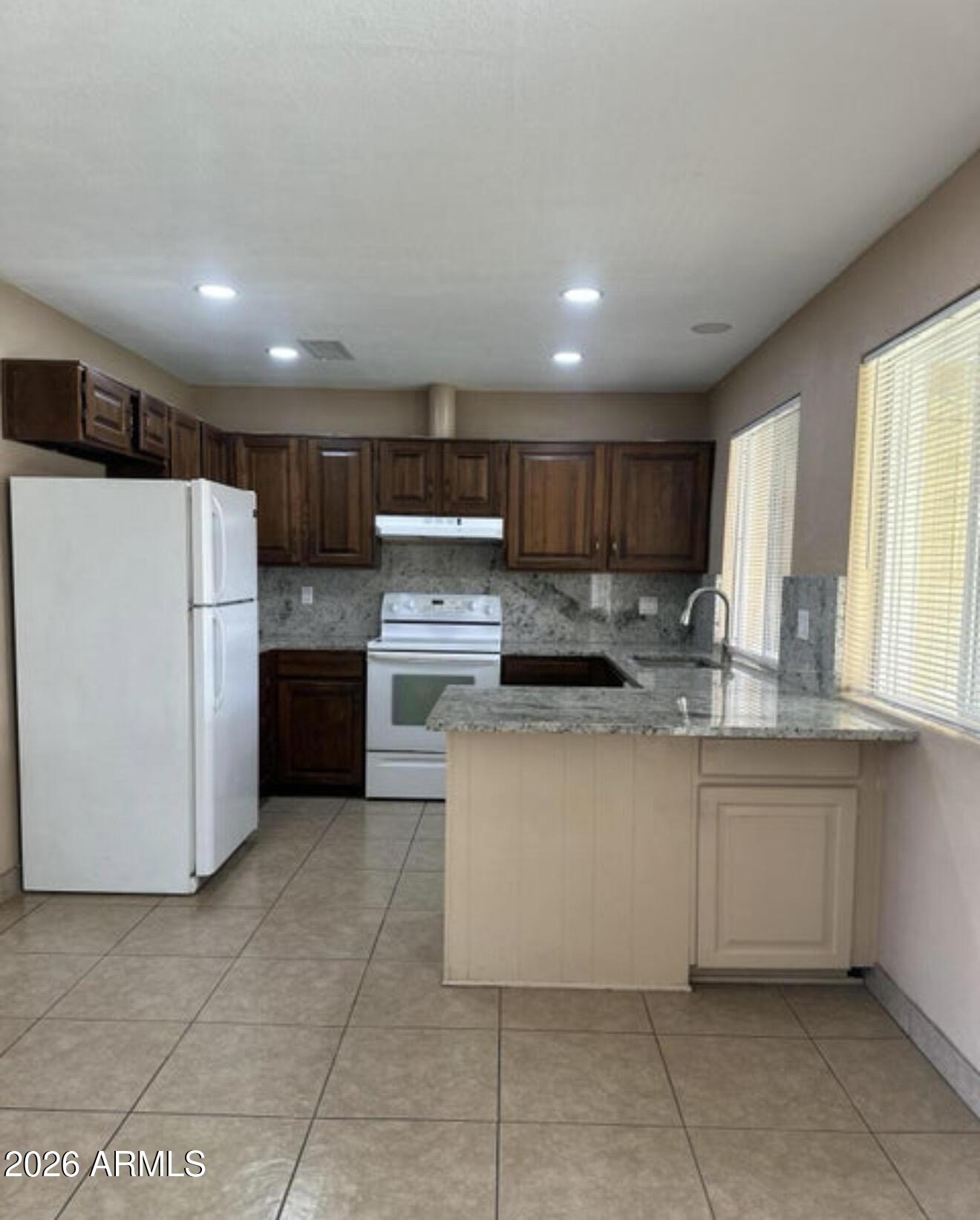 2916 North 87th Lane Phoenix, AZ 85037 - Photo 7 of 16 a kitchen with a cabinets and white stainless steel appliances
