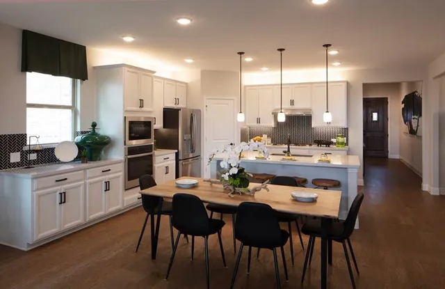 a kitchen with kitchen island a dining table and chairs