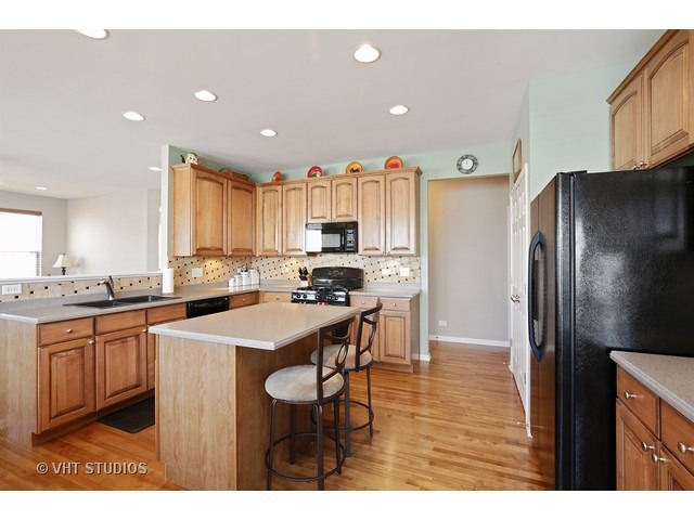 322 Monument Road Elgin, IL 60124 - Photo 3 of 15 a kitchen with stainless steel appliances a refrigerator a sink a stove a dining table and chairs