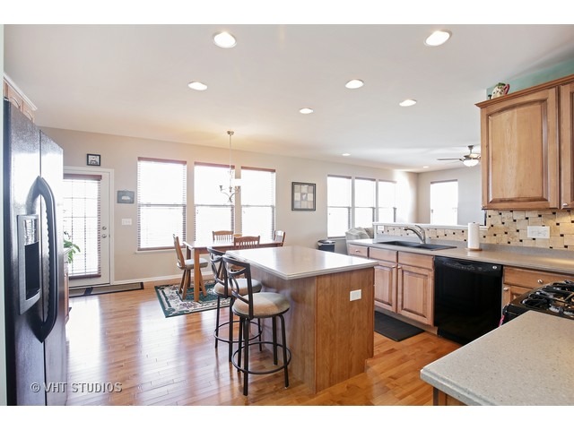 322 Monument Road Elgin, IL 60124 - Photo 4 of 15 a kitchen with stainless steel appliances kitchen island granite countertop a refrigerator a stove a sink dishwasher with a dining table and chairs