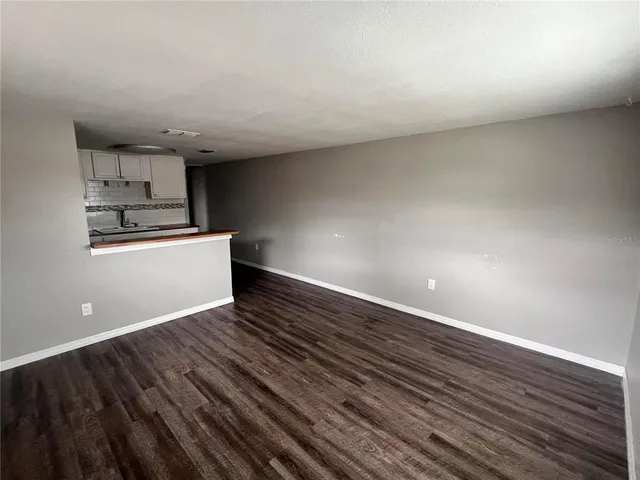 a view of kitchen and empty room with wooden floor