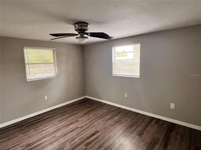 a view of an empty room with wooden floor and a window