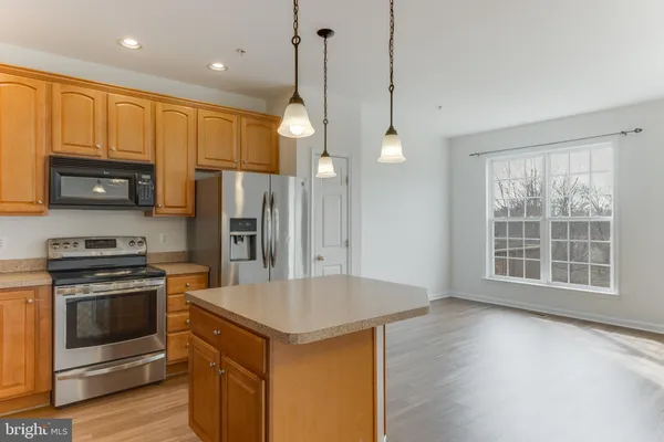 a kitchen with stainless steel appliances granite countertop a stove a refrigerator a sink a oven with wooden floor and cabinets