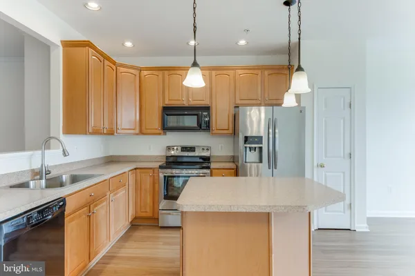 a kitchen with stainless steel appliances a stove center island a refrigerator and a sink