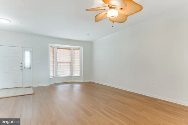 an empty room with wooden floor chandelier fan and windows