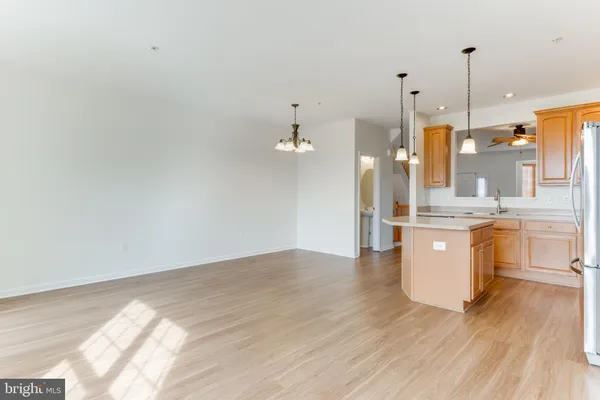 a view of a kitchen with kitchen island a sink wooden floor and a view of living room
