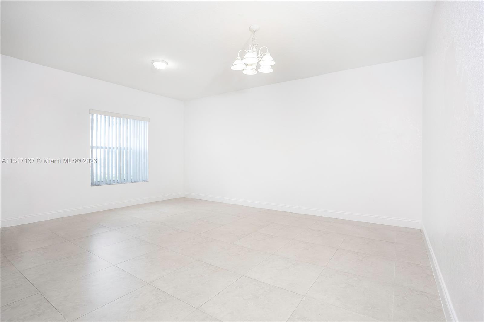 4971 Southwest 140th Terrace, Unit 6 Miramar, FL 33027 - Photo 5 of 24 an empty room with a chandelier fan and window