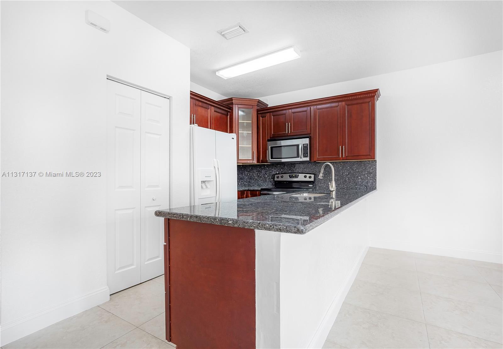 4971 Southwest 140th Terrace, Unit 6 Miramar, FL 33027 - Photo 8 of 24 a kitchen with stainless steel appliances granite countertop a sink stove and microwave