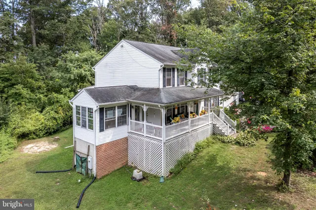 an aerial view of a house with yard and trees in the background