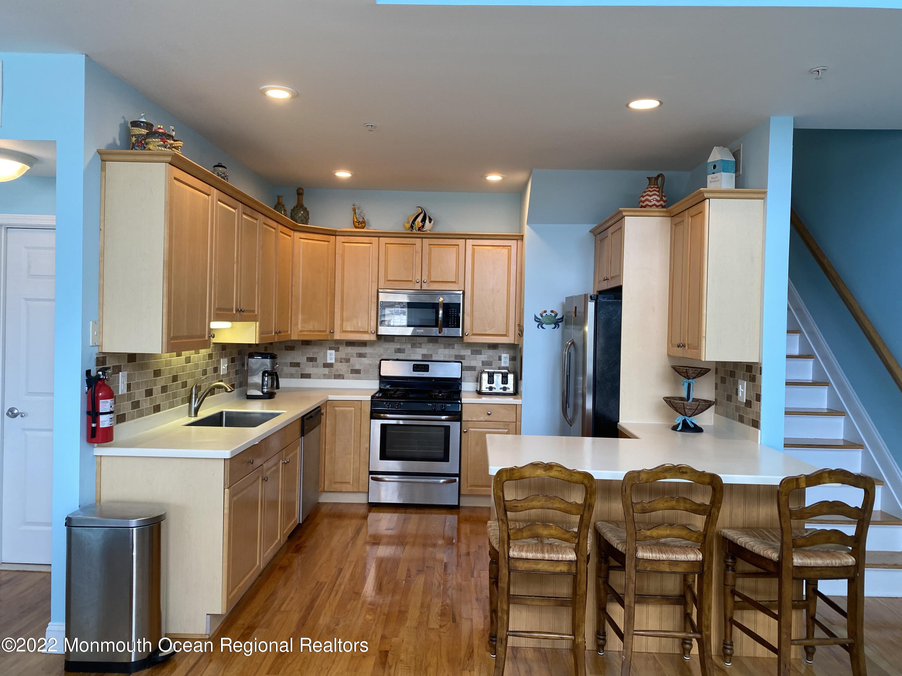 15 Sumner Avenue, Unit 12 Seaside Heights, NJ 08751 - Photo 5 of 24 a kitchen with stainless steel appliances kitchen island granite countertop a sink refrigerator and cabinets