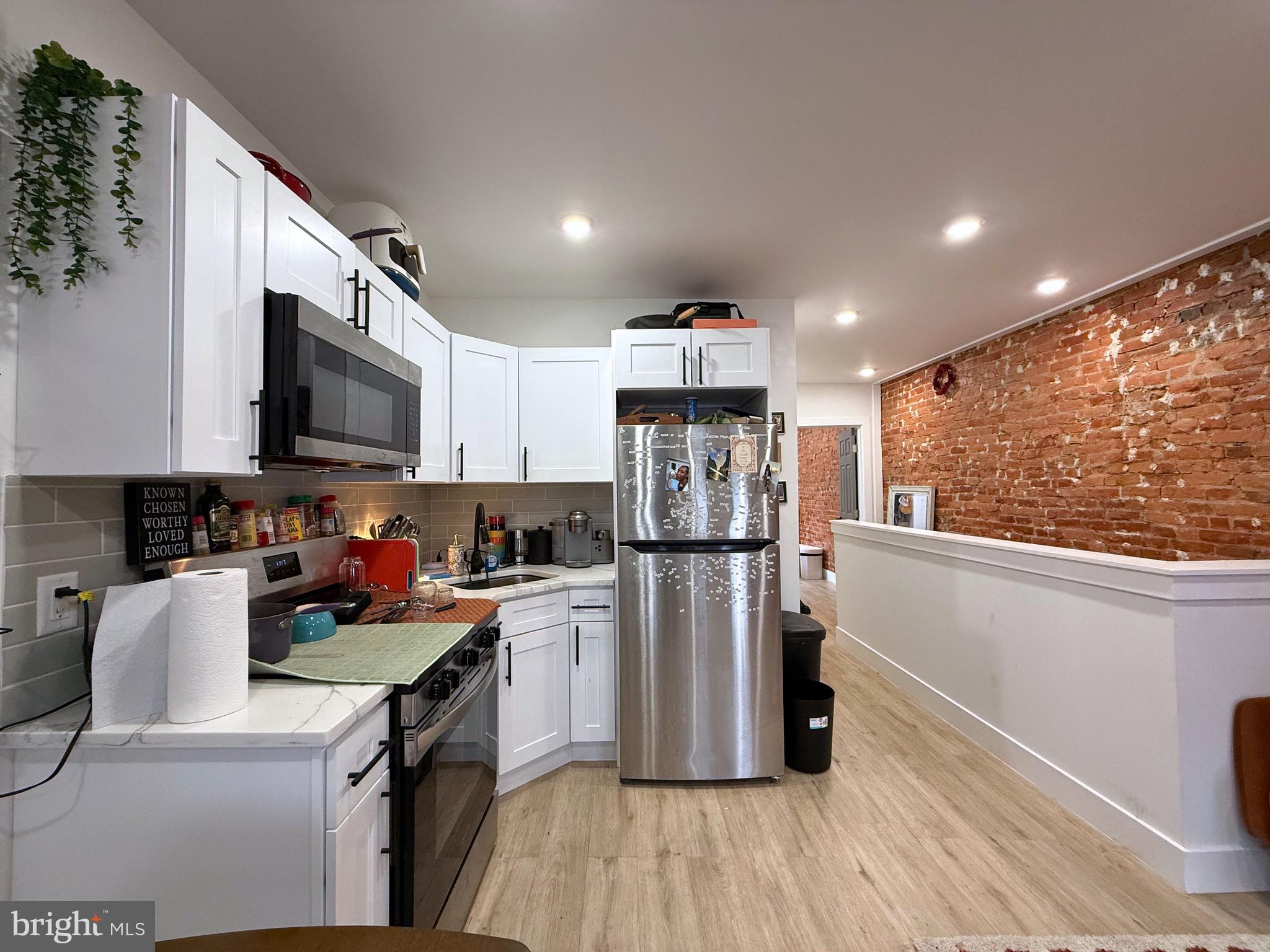 6136 Chancellor Street Philadelphia, PA 19139 - Photo 6 of 10 a kitchen with a refrigerator a stove top oven a sink dishwasher and wooden cabinets