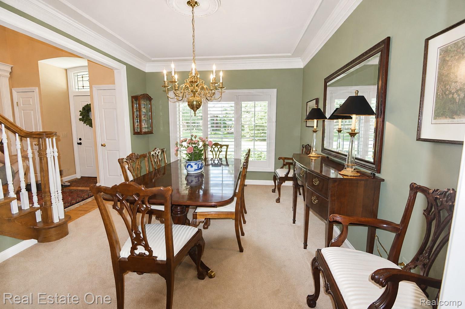 Formal dining area featuring a brass chandelier with decorative ceiling medallion, extensive crown molding, a tray ceiling, and plantation shutters