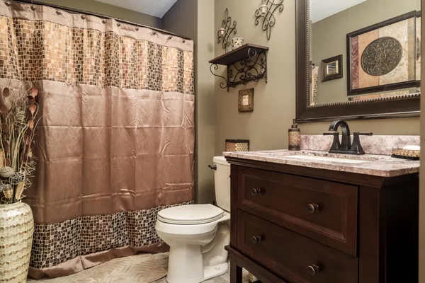 a bedroom with a bed and a lamp on dresser with wooden floor