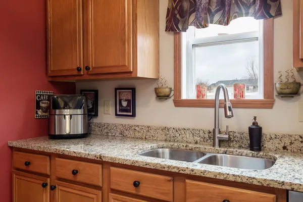 a kitchen with stainless steel appliances granite countertop a white stove top oven a dining table and chairs with wooden floor