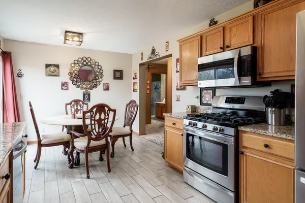 a kitchen with stainless steel appliances granite countertop a stove top oven a dining table and chairs with wooden floor