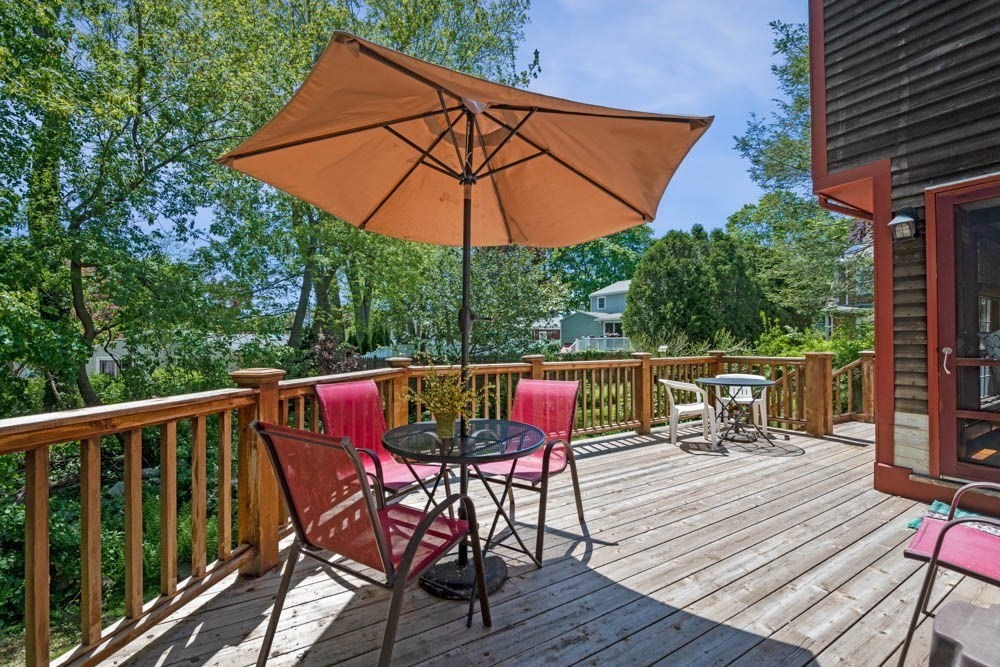 3 E Road Marblehead, MA 01945 - Photo 4 of 17 a view of deck with dinning table and chair under an umbrella with wooden floor