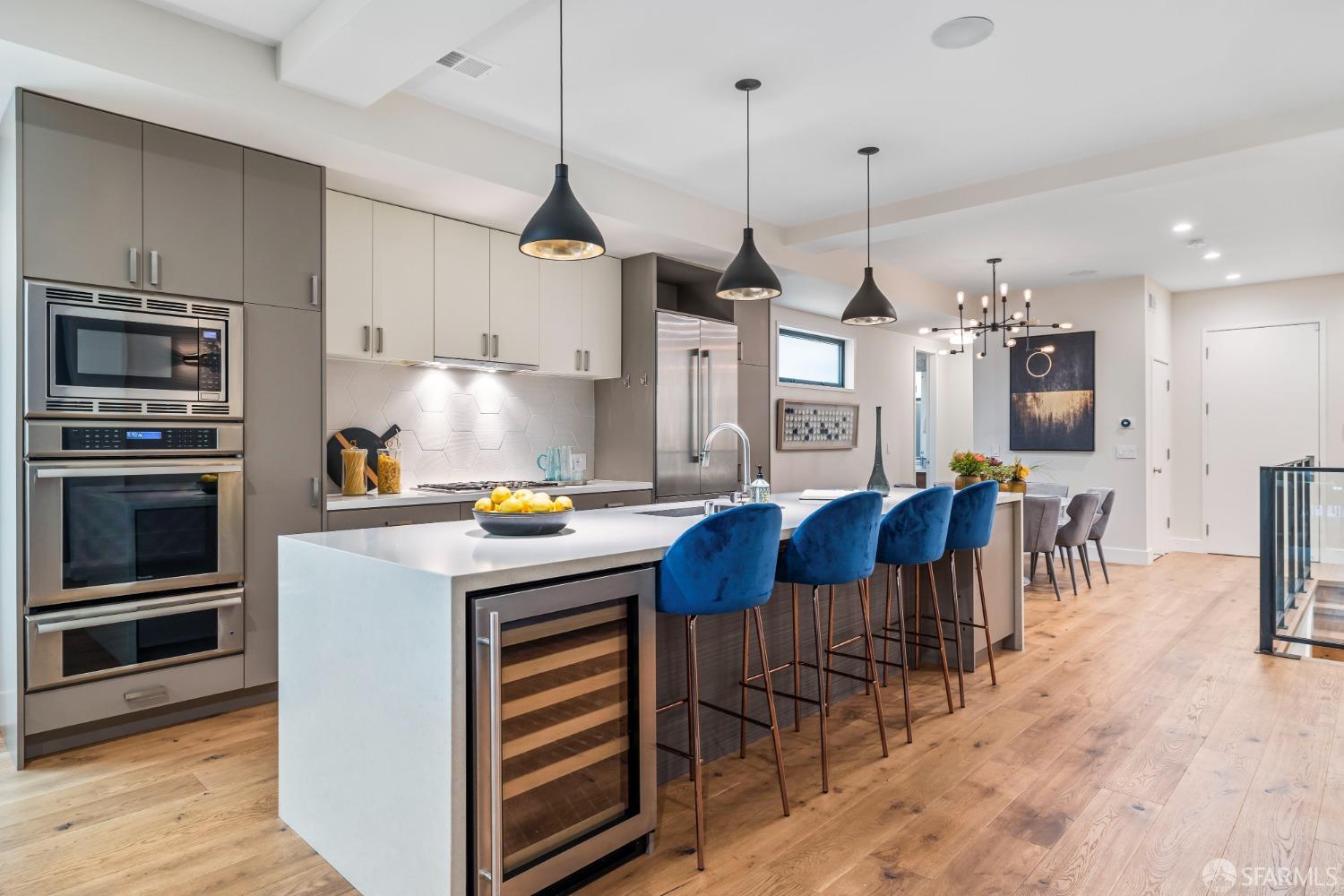 a kitchen with stainless steel appliances granite countertop a stove a refrigerator a kitchen island a sink a dining table and chairs with wooden floor