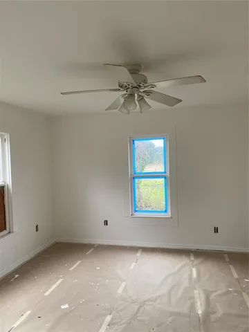 an empty room with a window and a fan