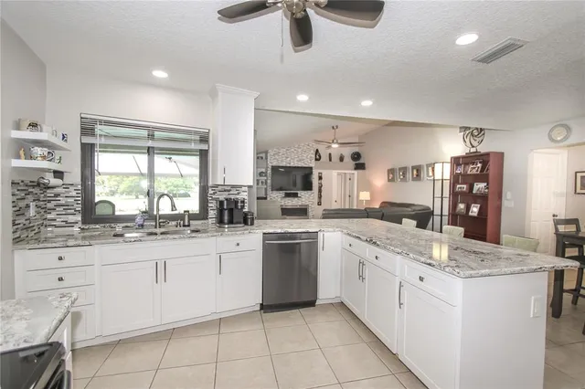 a kitchen with granite countertop white cabinets white appliances with sink and window