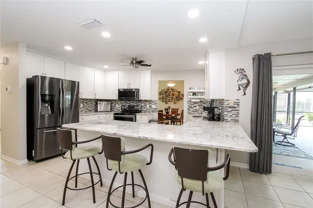 a kitchen with stainless steel appliances granite countertop a refrigerator a sink a stove a dining table and chairs