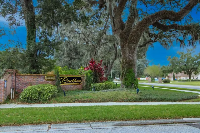 a sign board with tall trees in the background