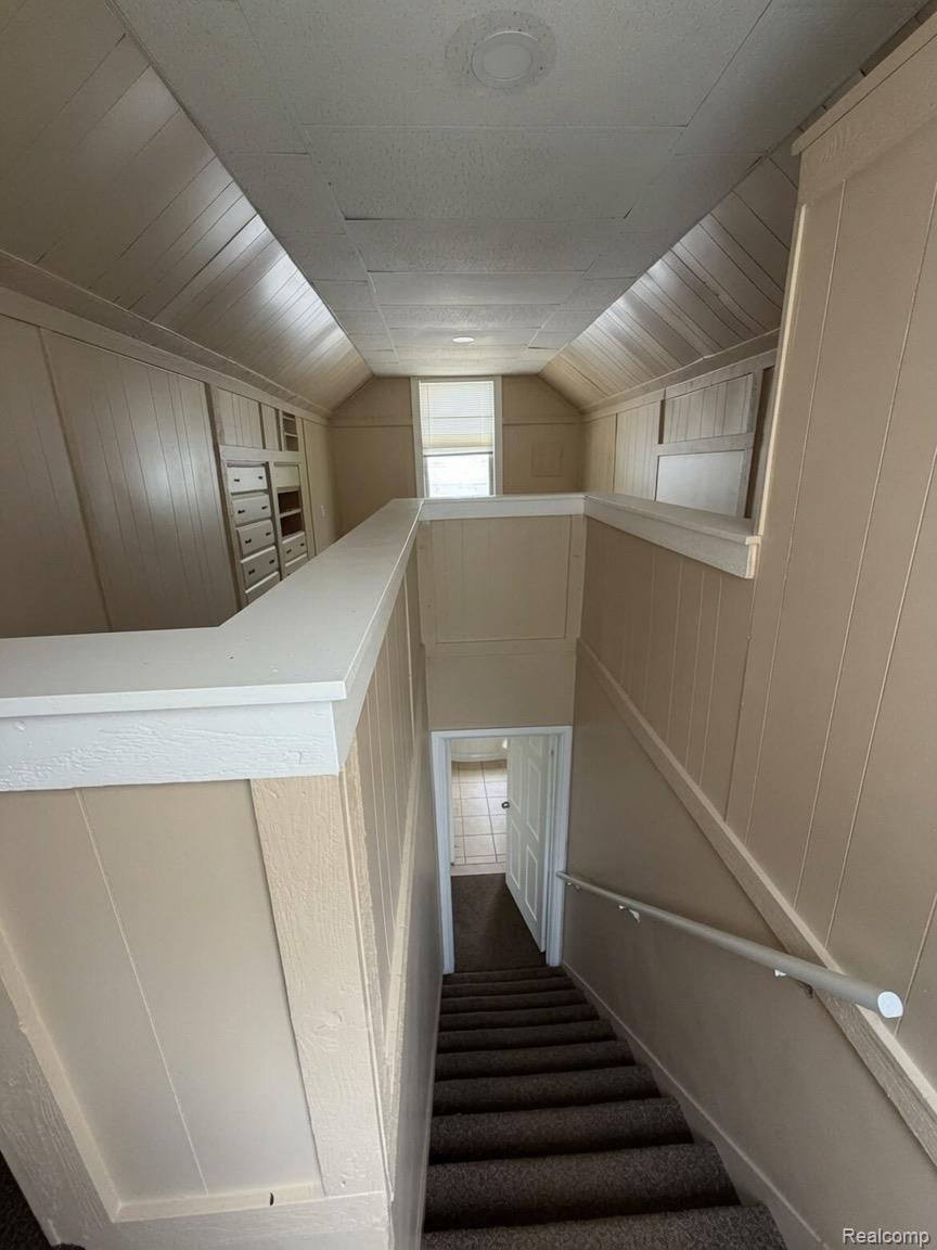 7286 Faust Avenue Detroit, MI 48228 - Photo 9 of 19 Carpeted staircase with wall-mounted handrail, leading to a hallway with tile flooring