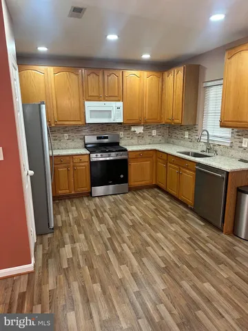 a large kitchen with granite countertop a sink a stove cabinets and wooden floor