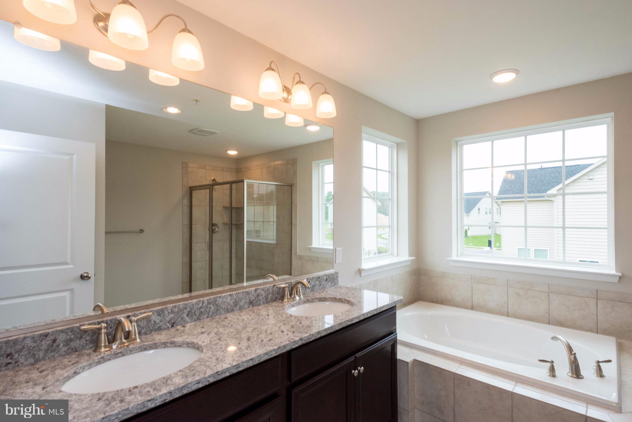 9766 Powder Hall Road Perry Hall, MD 21128 - Photo 18 of 30 a bathroom with a granite countertop sink a large mirror and a bathtub next to a window