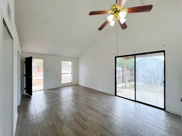 a view of an empty room with window and wooden floor