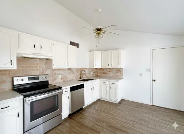 a kitchen with granite countertop a stove cabinets and wooden floor