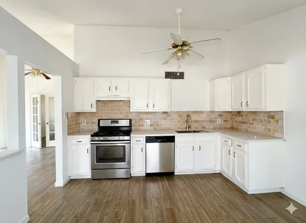 a kitchen with granite countertop a stove top oven a sink and white cabinets