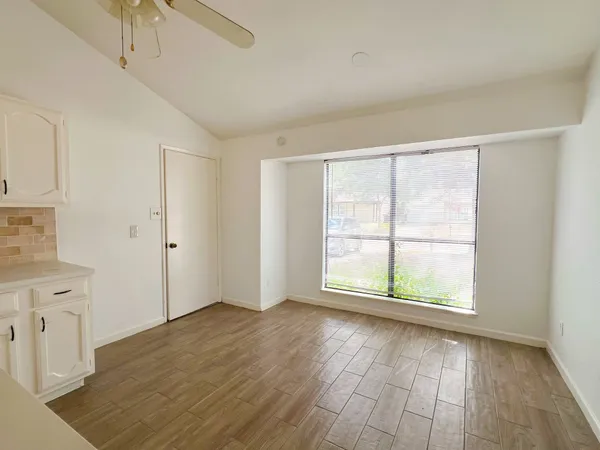 an empty room with wooden floor and windows