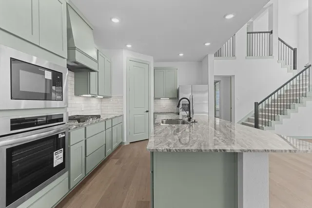 a kitchen with stainless steel appliances granite countertop a sink stove and refrigerator