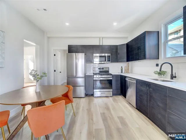 a kitchen with stainless steel appliances kitchen island granite countertop a sink refrigerator and cabinets